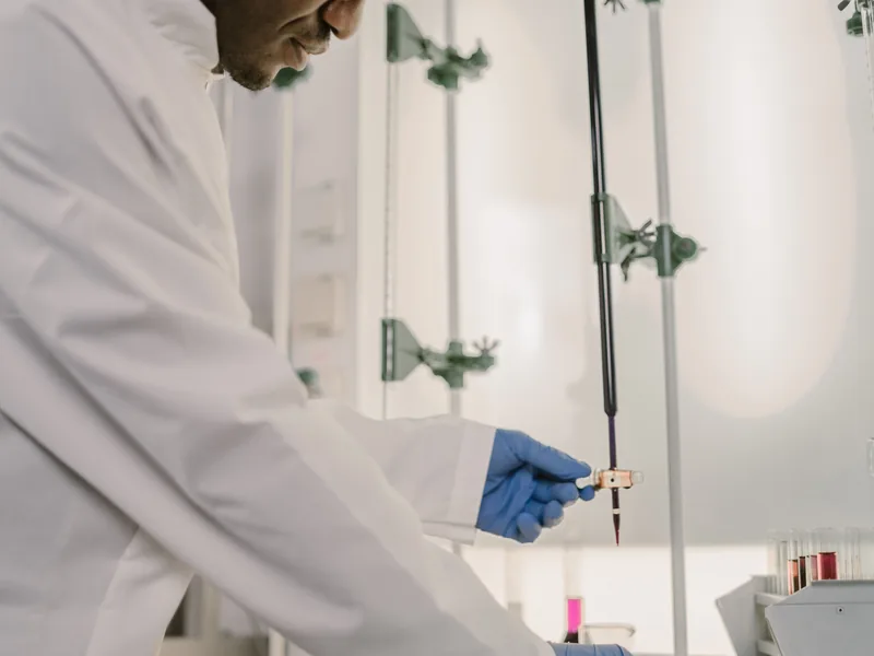 Un technicien de laboratoire manipule une pipette au-dessus d'une paillasse.