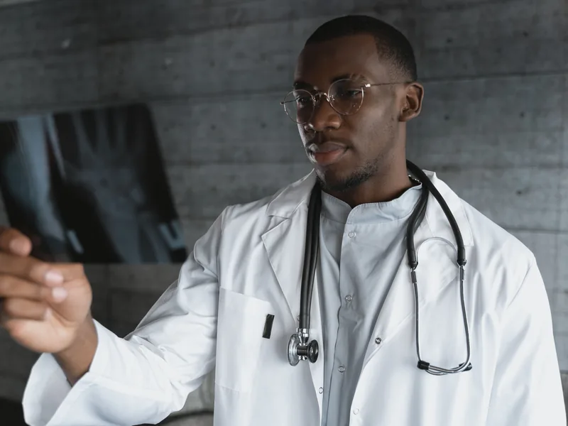 Un médecin examine un cliché radiographique à contre-jour.