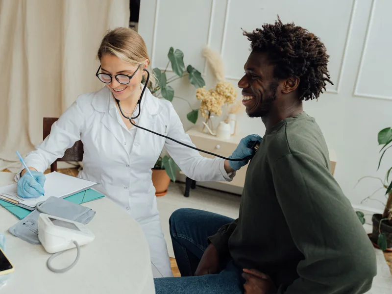 Une médecin ausculte un patient au stéthoscope pendant une consultation.
