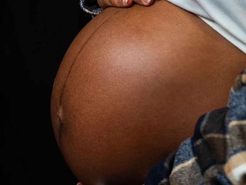 Une femme enceinte tient son ventre arrondi entre ses mains.
