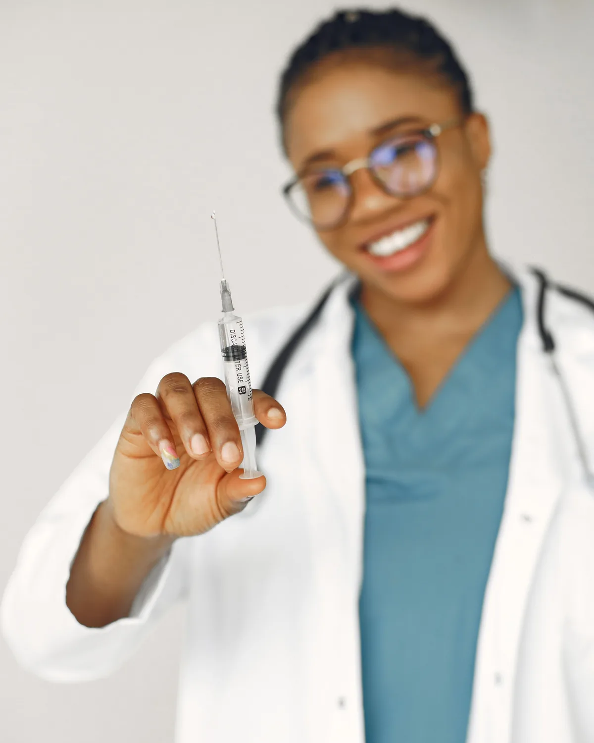 Une professionnelle de santé en blouse blanche tient une seringue préparée.